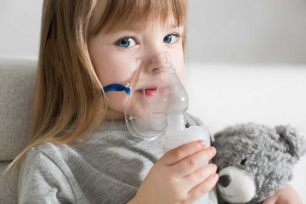 dziewczynka chora na astme trzyma przy twarzy inhalator